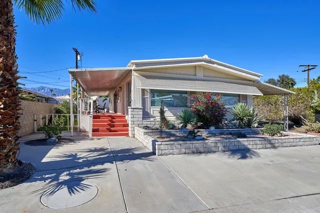 a view of a house with a yard and potted plants