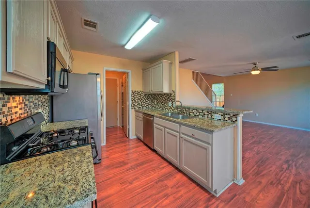 a kitchen with stainless steel appliances granite countertop a stove and a wooden floors