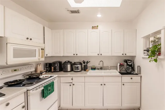 a kitchen with white cabinets and appliances
