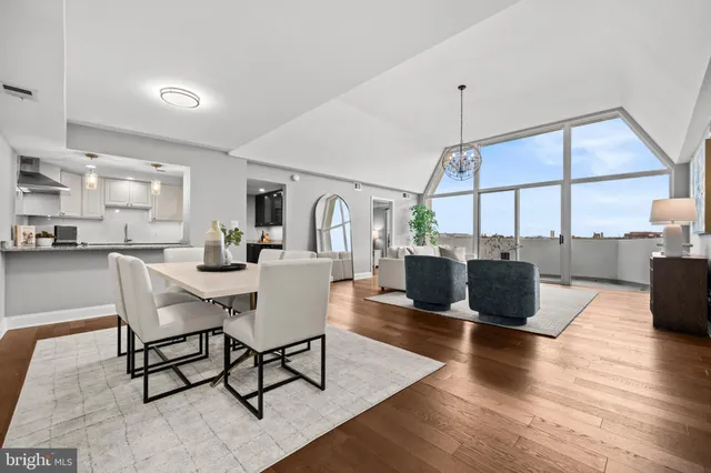 a living room with couches chairs and kitchen view with wooden floor