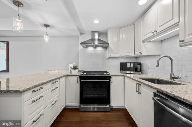 a kitchen with granite countertop a stove sink and cabinets