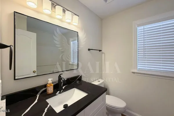 a bathroom with a granite countertop sink vanity mirror and toilet