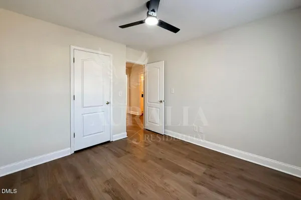 an empty room with wooden floor and ceiling fan