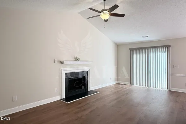 an empty room with windows fireplace and fan