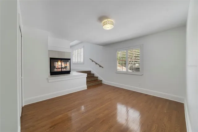 a view of an empty room with a window and a kitchen