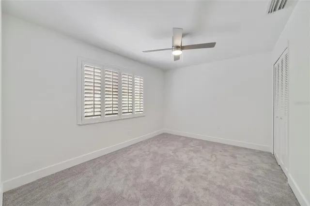 an empty room with a window and ceiling fan