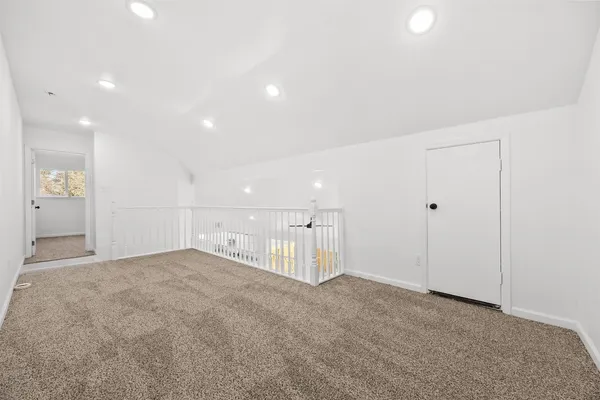an empty room with a chandelier fan and windows