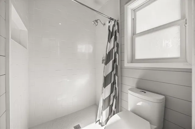 a white toilet sitting next to a window in a bathroom