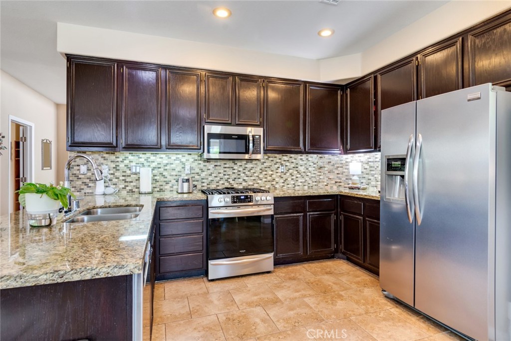20885 Bakal Drive Riverside, CA 92508 - Photo 13 of 47 a kitchen with stainless steel appliances granite countertop wooden cabinets a refrigerator and a sink
