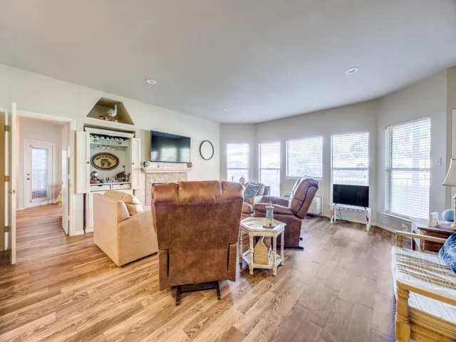 a living room with furniture a large window and wooden floor