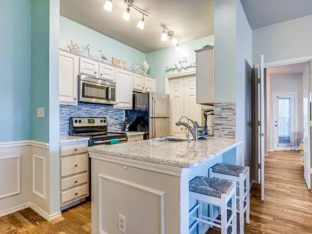 a kitchen with kitchen island granite countertop a stove top oven a sink a counter space and cabinets