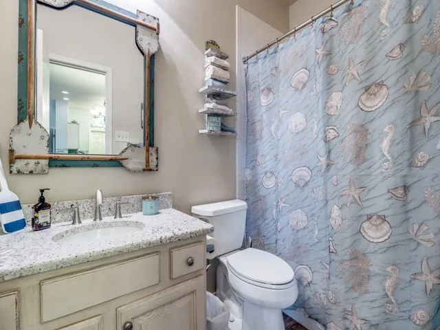 a bathroom with a granite countertop sink a toilet and a mirror