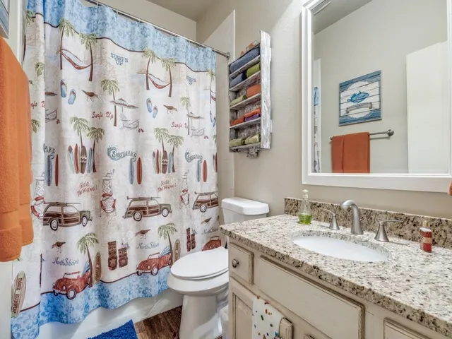 a bathroom with a granite countertop toilet sink and mirror