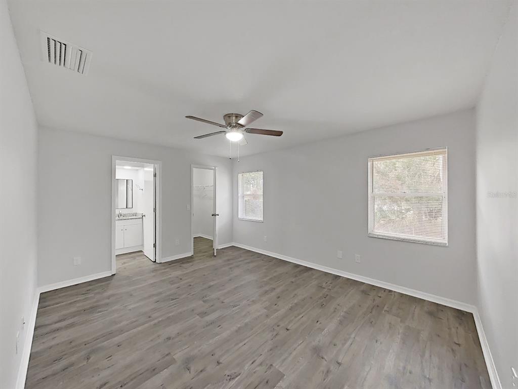 902 Great Pine Point Inverness, FL 34452 - Photo 19 of 39 an empty room with wooden floor chandelier fan and windows