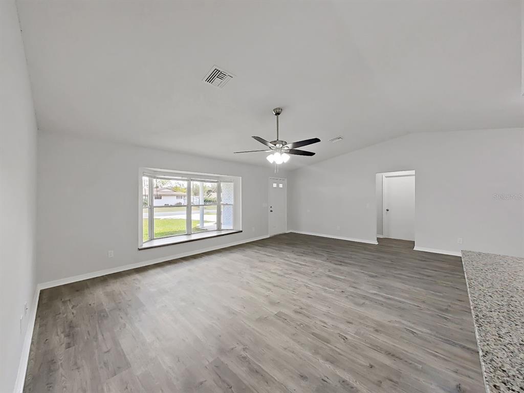 902 Great Pine Point Inverness, FL 34452 - Photo 8 of 39 an empty room with wooden floor ceiling fan and windows