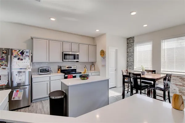 a kitchen with stainless steel appliances kitchen island granite countertop a table chairs sink and cabinets