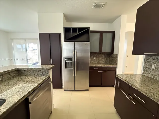a kitchen with stainless steel appliances granite countertop a sink and a refrigerator