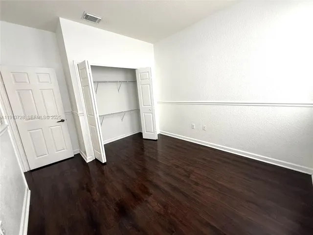 an empty room with wooden floor and white wall