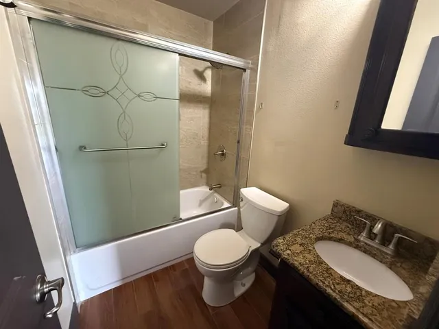a bathroom with a granite countertop sink toilet and a mirror