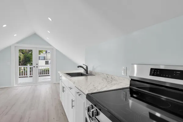 a kitchen with a stove a sink and wooden floor