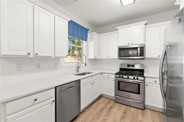 a kitchen with white cabinets stainless steel appliances and sink