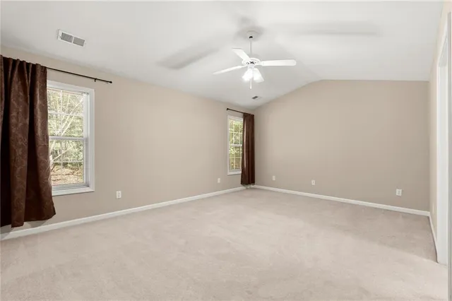 an empty room with windows and fan