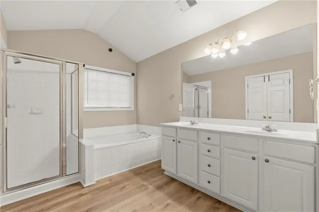 a bathroom with a double vanity sink a large mirror and a bathtub