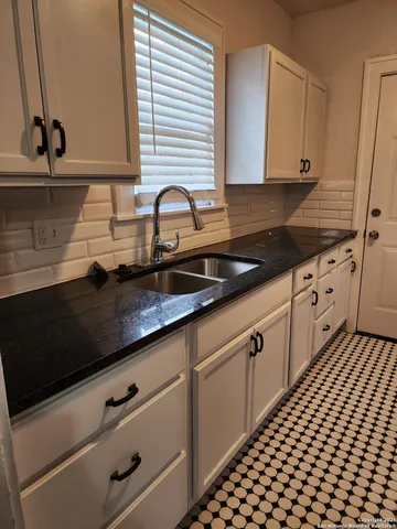 a kitchen with granite countertop white cabinets and black appliances