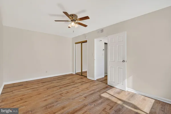 a view of empty room with wooden floor and fan