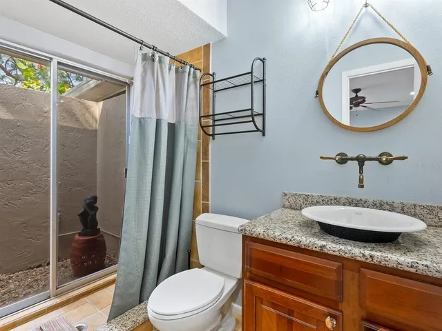 a bathroom with a granite countertop sink mirror vanity and toilet