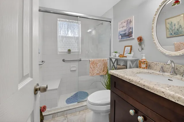 a bathroom with a granite countertop sink a toilet and a mirror