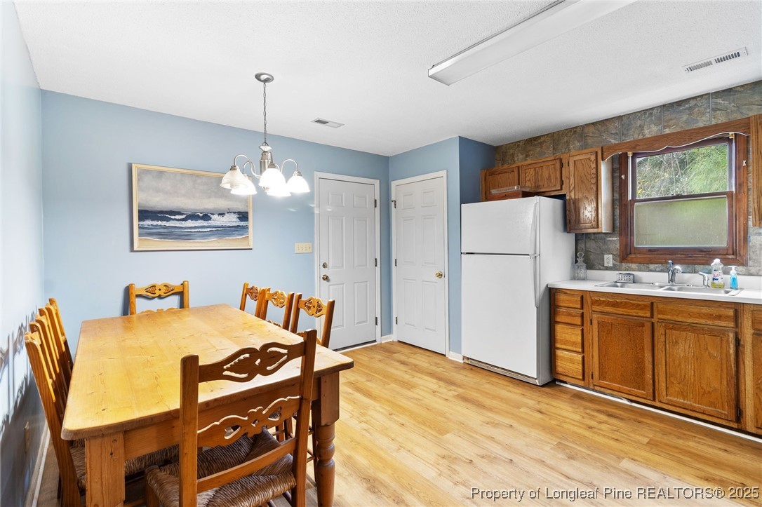 1132 Hoke Loop Road Fayetteville, NC 28314 - Photo 11 of 29 a view of a dining room with furniture a chandelier and a refrigerator