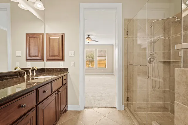 a bathroom with a granite countertop sink a mirror and shower
