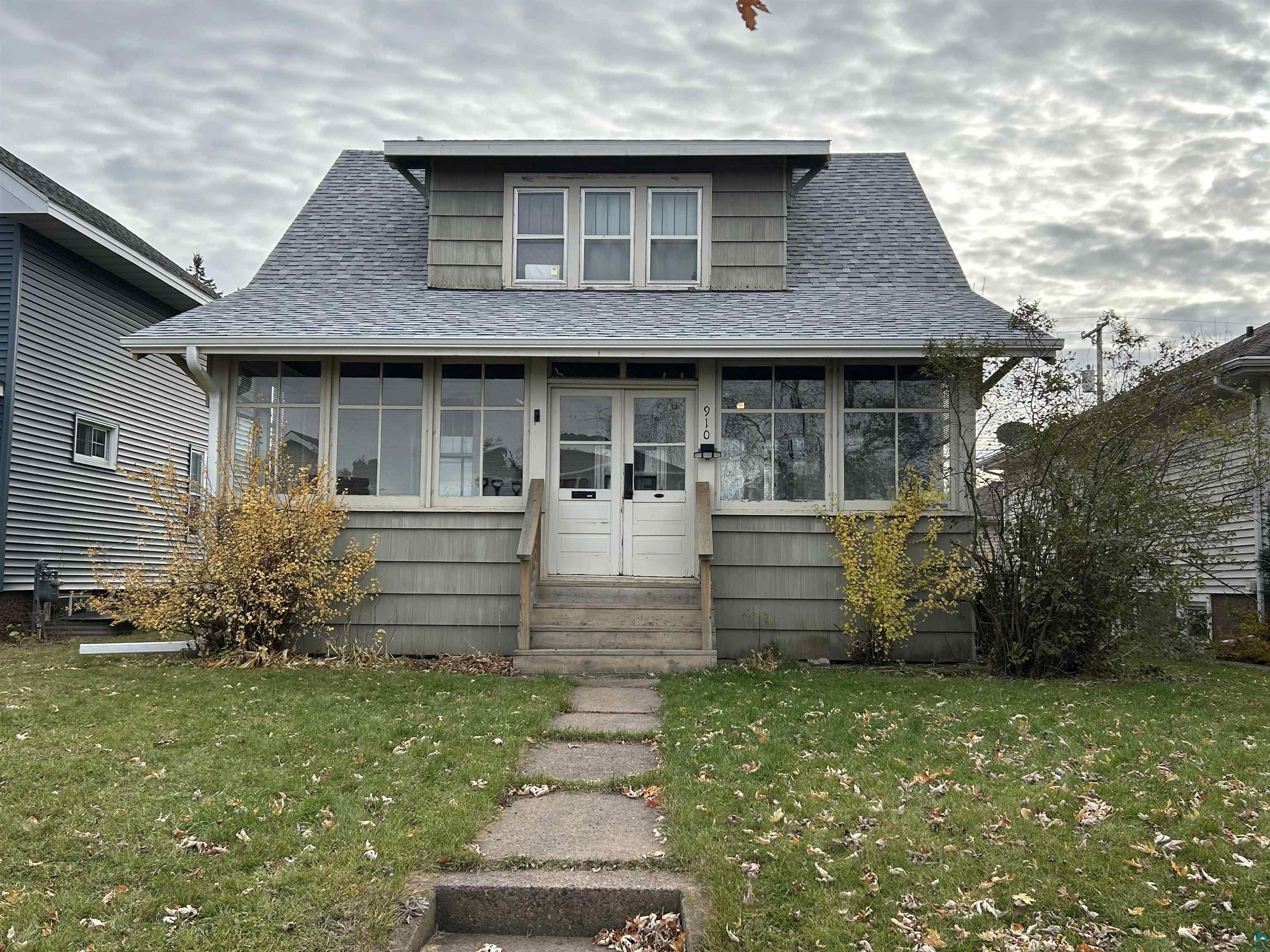 Bungalow featuring a sunroom, a front yard, a shingled roof, and entry steps