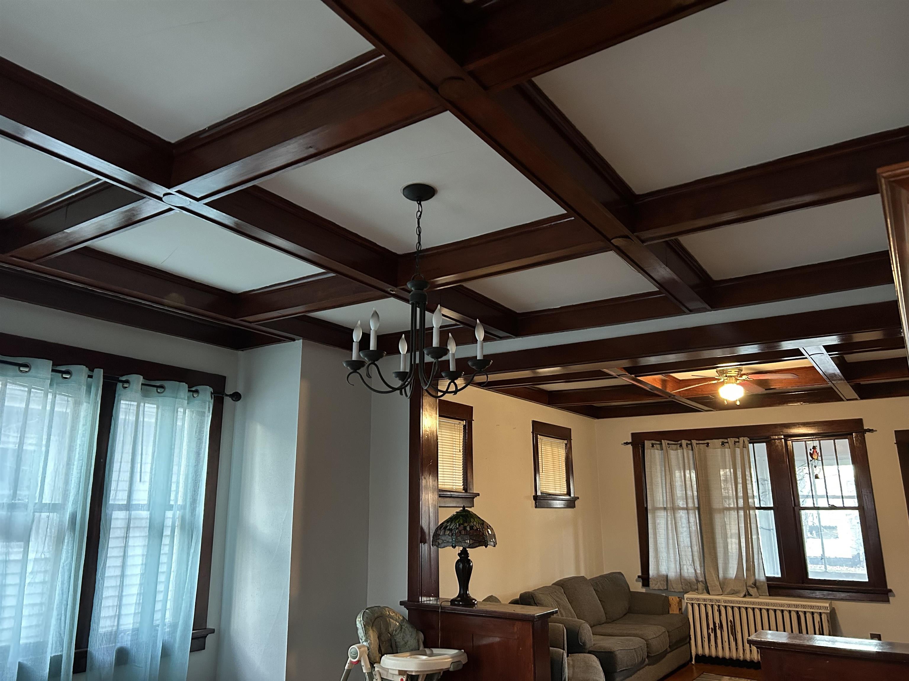 910 North 20th Street Superior, WI 54880 - Photo 26 of 39 Living room featuring coffered ceiling, radiator heating unit, beamed ceiling, and a chandelier