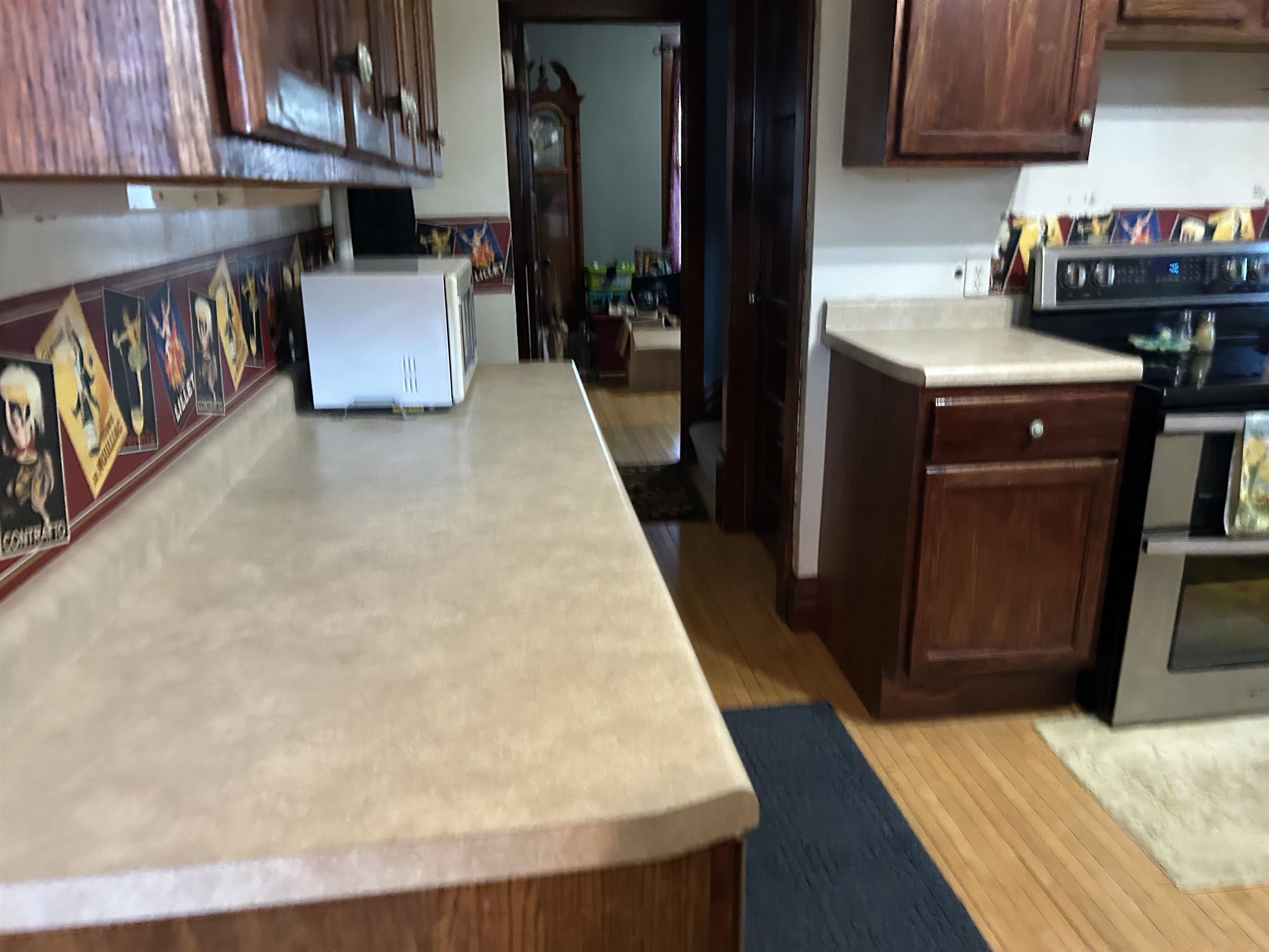 910 North 20th Street Superior, WI 54880 - Photo 27 of 39 Kitchen featuring light countertops, range with two ovens, white microwave, light wood-style flooring, and dark brown cabinets