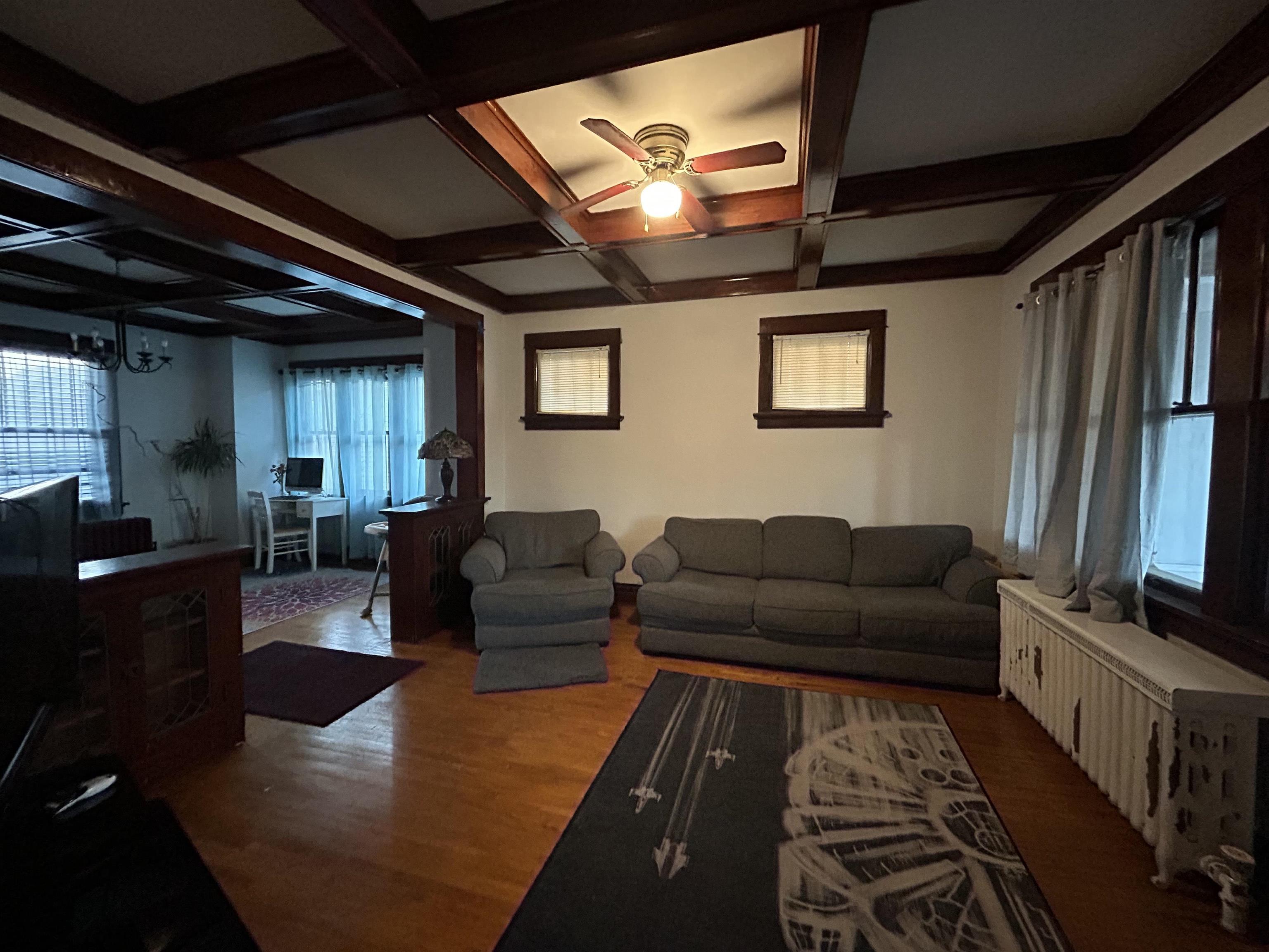 910 North 20th Street Superior, WI 54880 - Photo 29 of 39 Living area featuring wood finished floors, a ceiling fan, beam ceiling, and coffered ceiling