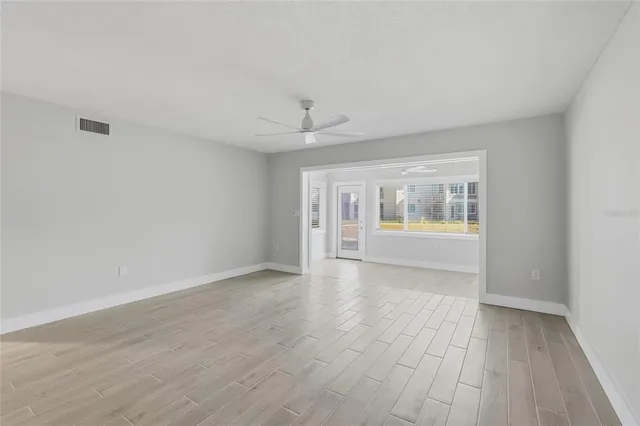 a view of an empty room with a window and wooden floor