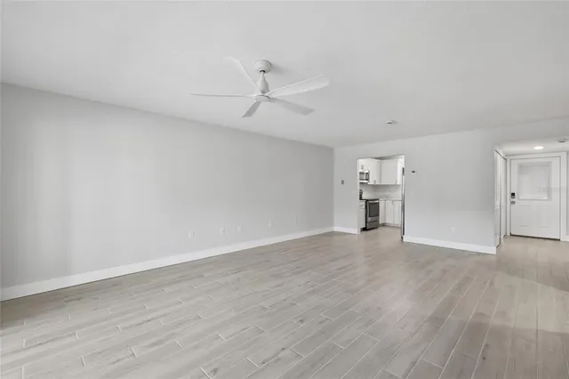 a view of empty room with wooden floor and ceiling fan
