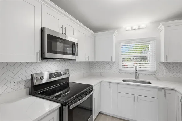 a kitchen with cabinets stainless steel appliances a sink and a window