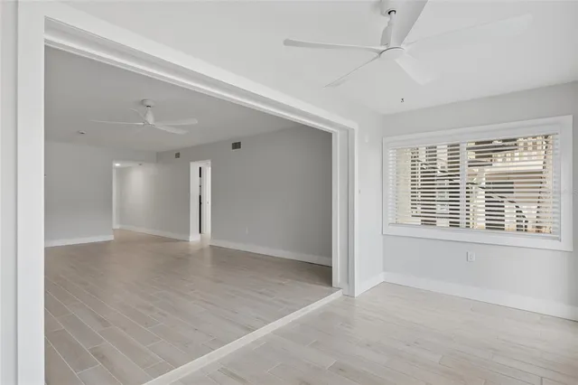 a view of an empty room with wooden floor and a window