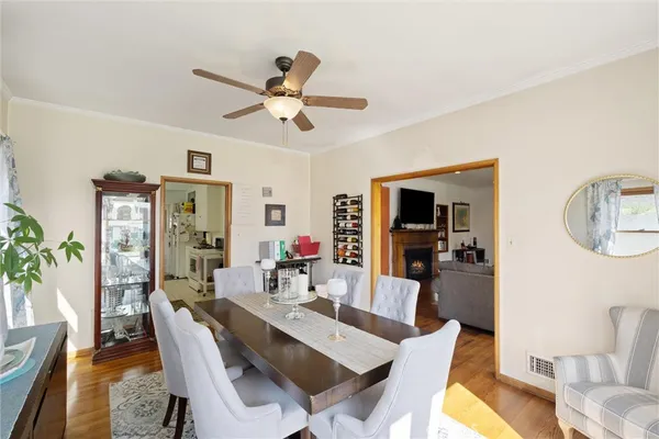 a dining room with wooden floor a chandelier fan a wooden table and chairs