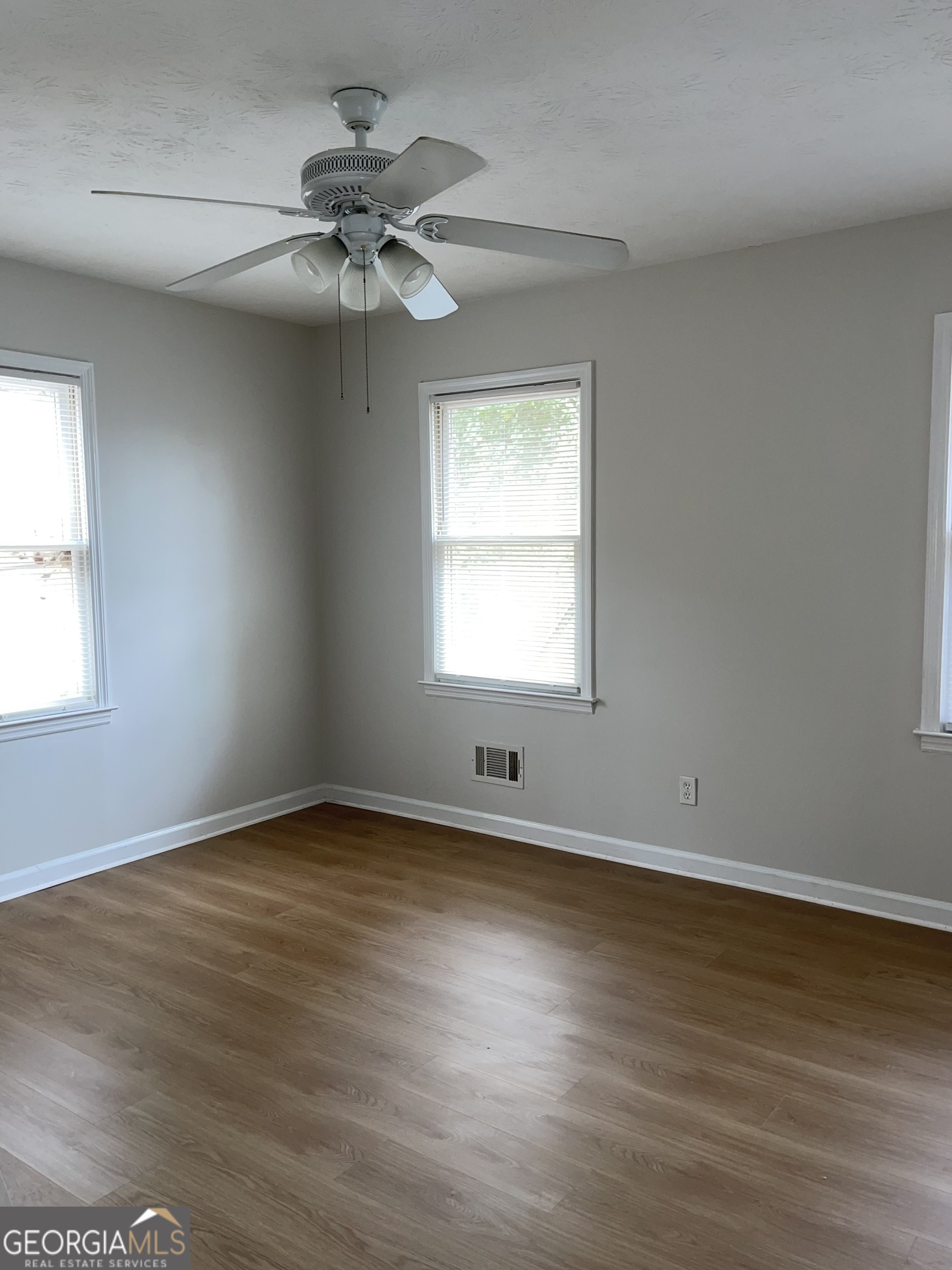 764 Hemphill Road Stockbridge, GA 30281 - Photo 11 of 14 an empty room with wooden floor chandelier fan and windows