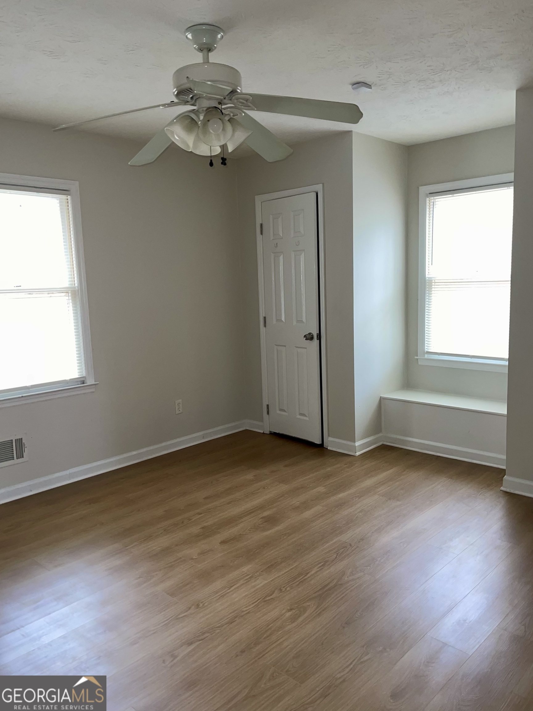 764 Hemphill Road Stockbridge, GA 30281 - Photo 9 of 14 an empty room with wooden floor chandelier fan and windows