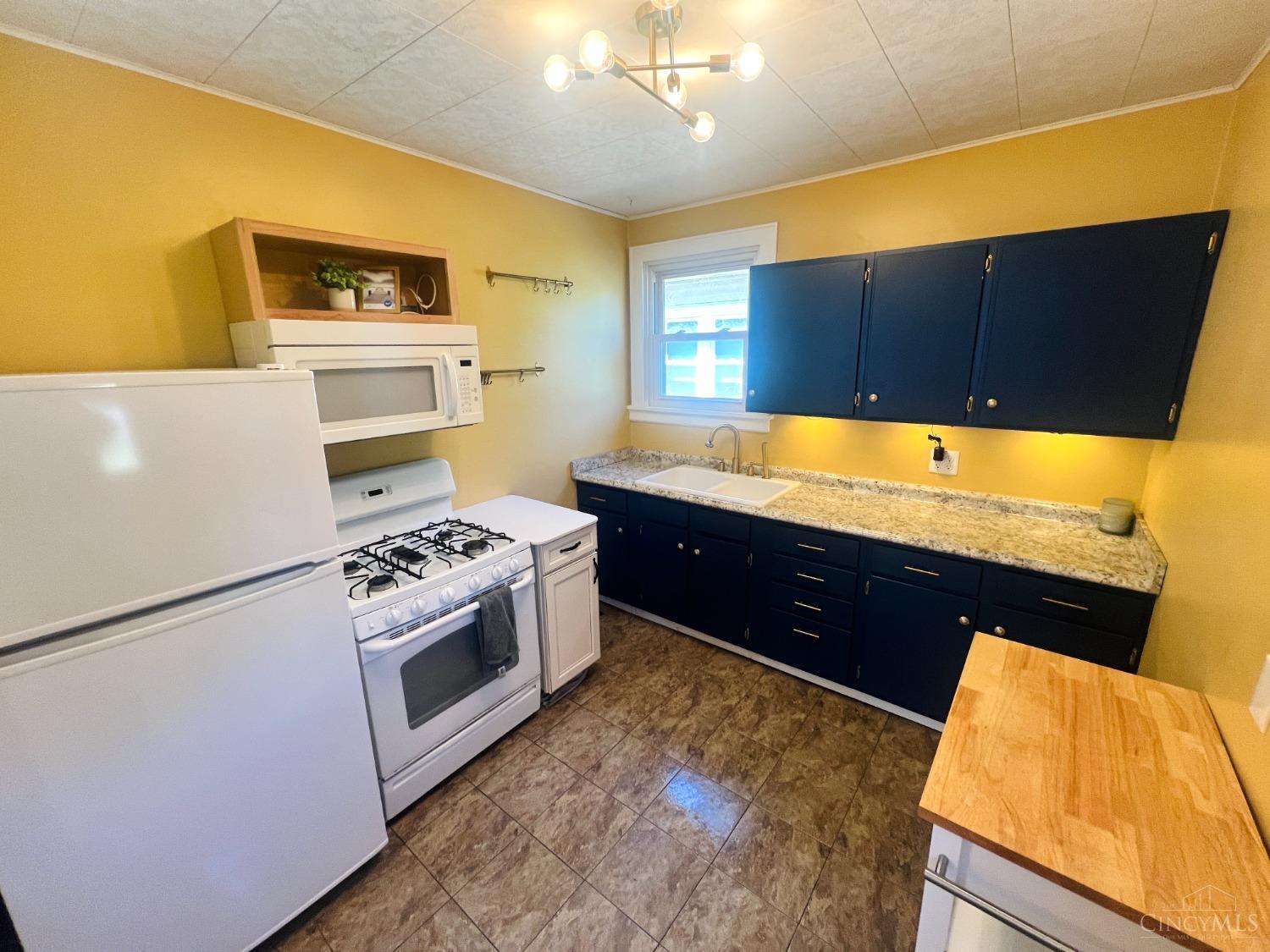 3904 Watterson Road Cincinnati, OH 45227 - Photo 10 of 19 Bright cheery kitchen features navy cabinets, new countertops with under cabinet lighting and a new refrigerator + microwave in 2022. Kitchens opens to back yard.