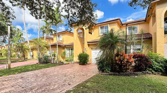 a front view of a house with a yard and palm trees