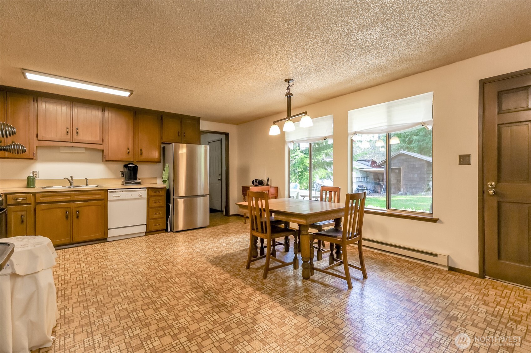 4701 292nd Street East Graham, WA 98338 - Photo 12 of 40 a kitchen with a table chairs refrigerator and cabinets
