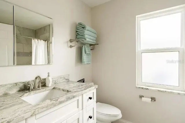 a bathroom with a granite countertop sink toilet and mirror