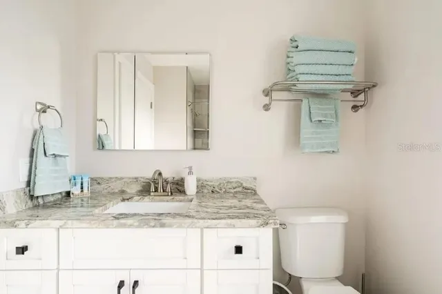 a bathroom with a granite countertop sink a mirror and a toilet
