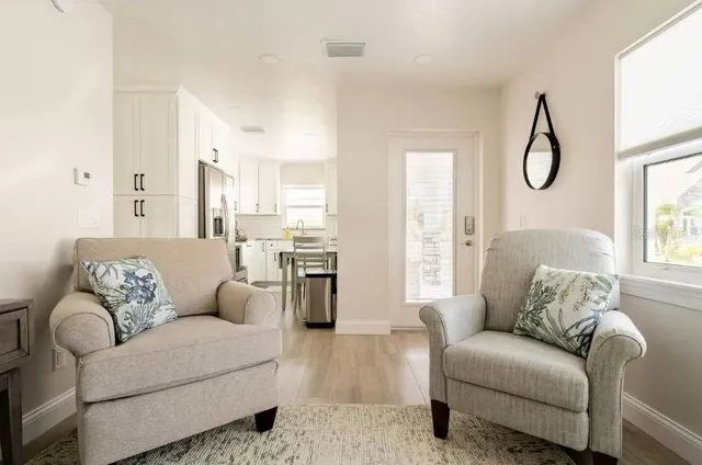 a living room with furniture white walls and glass windows